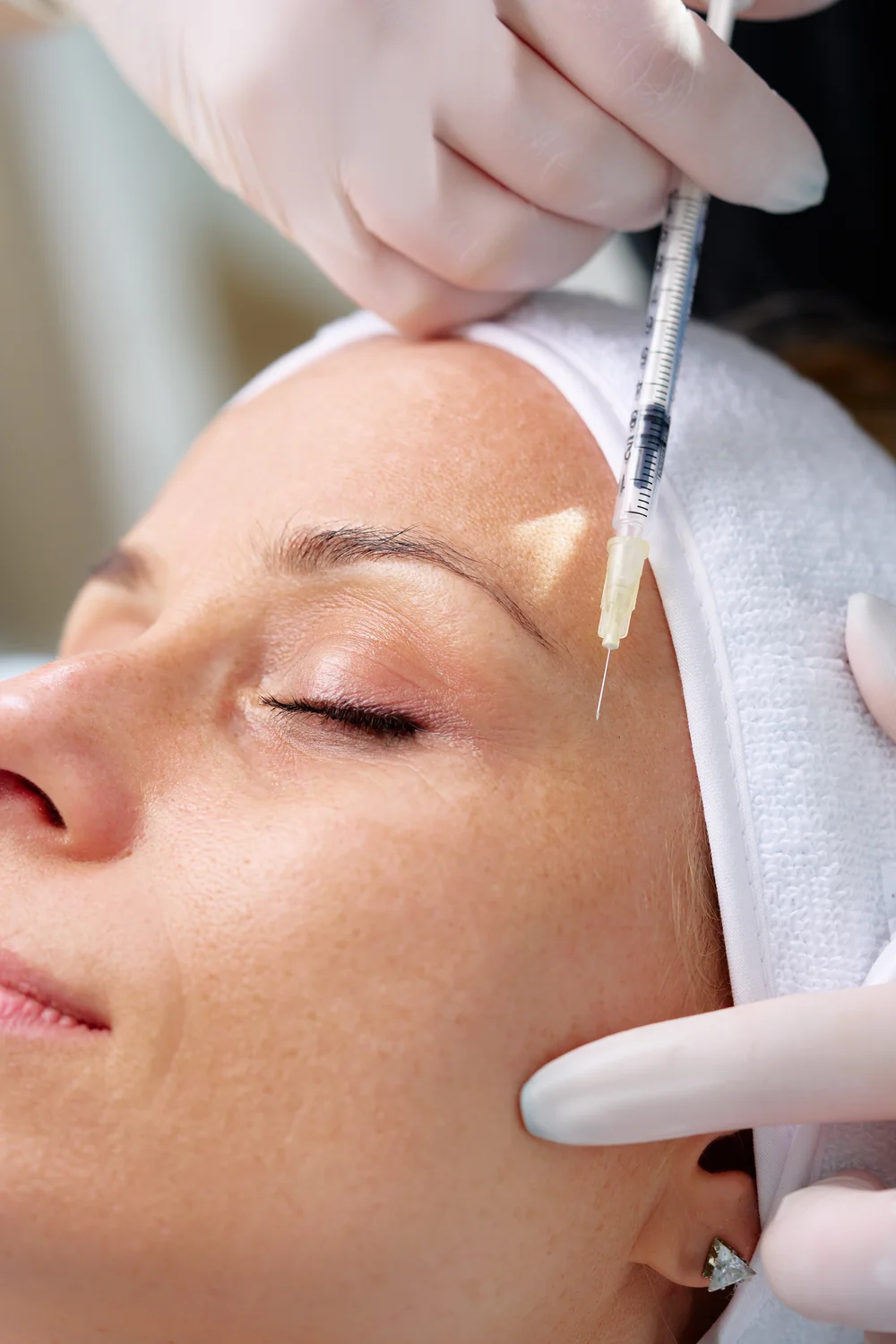 Woman receives cosmetic injection in clinical setting, enhancing beauty using modern techniques.