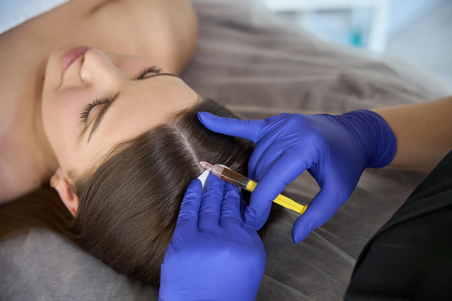 Close-up of applying serum to roots with a precision dropper on red hair, showcasing hair care routine.